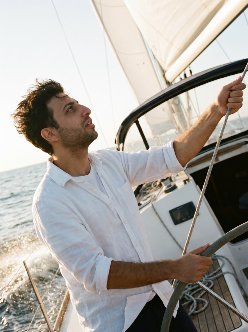 Alon at the helm of a sailboat at golden hour